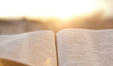 Open Bible with bright sunset in the background.